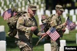Ahead of Memorial Day, members of the U.S. armed forces place flags in front of more than 260,000 headstones at Arlington National Cemetery, in Arlington, Virginia, May 27, 2021.