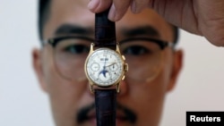 Seorang petugas memamerkan jam tangan Patek Philippe emas 18 karat dengan kalender abadi dan fase bulan milik Raja Farouk di lelang Christie's, di Dubai, Uni Emirat Arab, 19 Maret 2018.