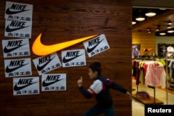 A child runs past protest signs pasted around a Nike logo in support of the strike by workers of Yue Yuen Industrial Holdings in Dongguan, during an International Labour Day rally in Hong Kong May 1, 2014.