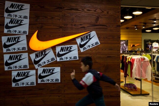 A child runs past protest signs pasted around a Nike logo in support of the strike by workers of Yue Yuen Industrial Holdings in Dongguan, during an International Labour Day rally in Hong Kong May 1, 2014.