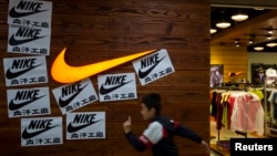 A child runs past protest signs pasted around a Nike logo in support of the strike by workers of Yue Yuen Industrial Holdings in Dongguan, during an International Labour Day rally in Hong Kong May 1, 2014.