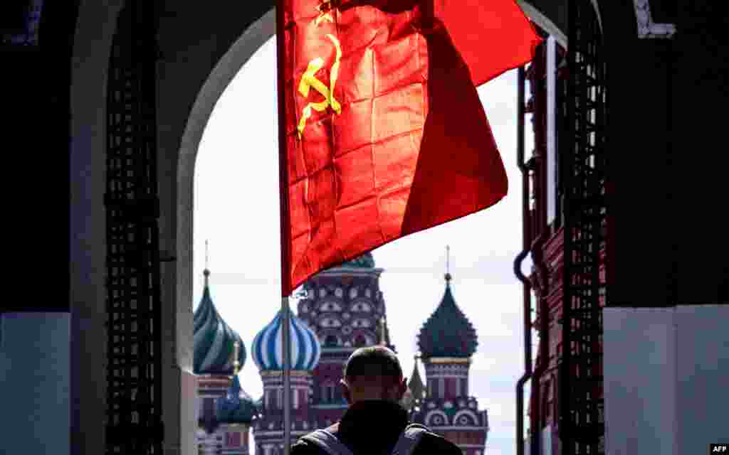 A Russian Communist party supporter carries a red flag as he walks along Red Square in Moscow. The Labour Day celebrations were canceled due to pandemic threat of COVID-19.