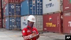 FILE - A worker makes a note near stacks of containers at an Indonesia Port Corporations terminal at Tanjung Priok Port in Jakarta, Indonesia, Oct. 8, 2021.