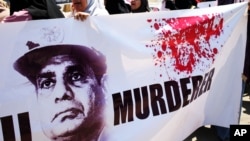 FILE - Supporters of ousted Egyptian President Mohammed Morsi carry a banner against Abdel Fattah el-Sissi during a demonstration in front of the National Council for Human Right building in Cairo. 