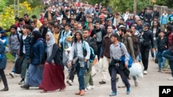 Migrants walk along a street after they arrived by train in Hegyeshalom, at the Austrian border, 169 km west of Budapest, Hungary, Oct. 7, 2015.