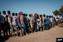 FILE - Ethiopian refugees who fled the Ethiopia's Tigray conflict wait in a line for the food distribution at the Um Rakuba refugee camp in Sudan's eastern Gedaref state, Dec. 12, 2020.