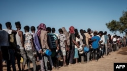 FILE - Ethiopian refugees who fled the Ethiopia's Tigray conflict wait in a line for the food distribution at the Um Rakuba refugee camp in Sudan's eastern Gedaref state, Dec. 12, 2020.