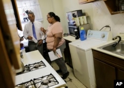 FILE - Jennifer Gomez talks with U.S. Rep. Adriano Espaillat about repairs needed in her apartment in public housing in New York, July 3, 2018.