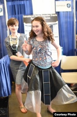 Allison Clausius (trái), đến từ Toledo, Ohio, nâng chiếc váy sạc điện thoại di động cho một cô gái trẻ mặc thử tại Cuộc thi ISEF ở Pittsburgh. (Ảnh: Intel)
