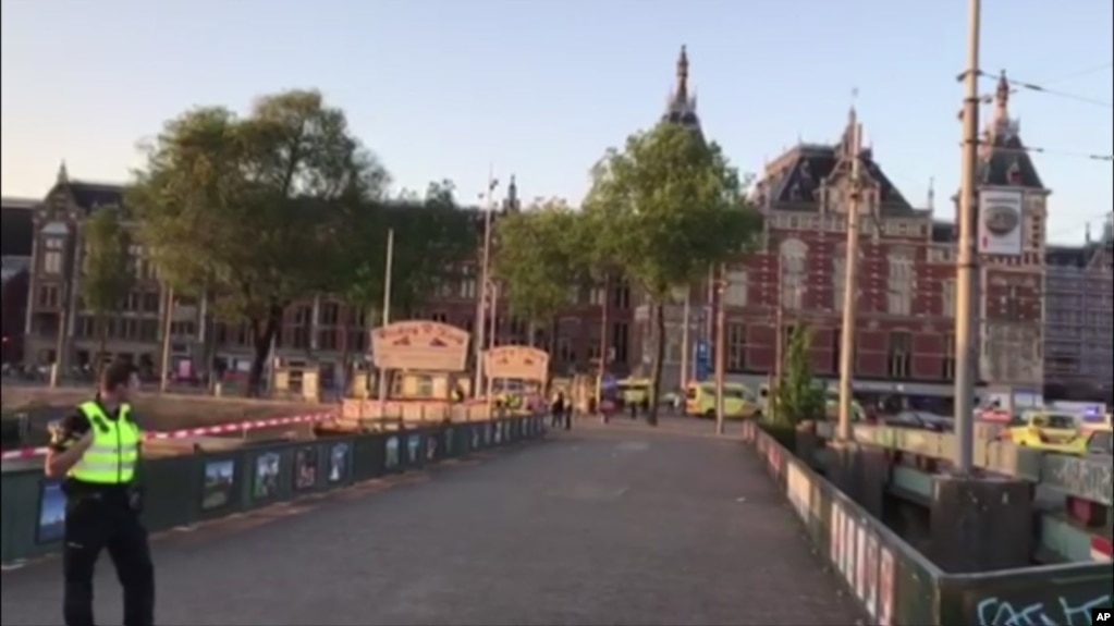 This image taken from video shows a security officer standing outside Amsterdam Central Station in Amsterdam, June 10, 2017. A car struck pedestrians around Amsterdam's main train station on Saturday, injuring eight people.
