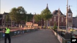 This image taken from video shows a security officer standing outside Amsterdam Central Station in Amsterdam, June 10, 2017. A car struck pedestrians around Amsterdam's main train station on Saturday, injuring eight people.