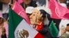 Manifestantes portan muñecos con la imagen del presidente Andrés Manuel López Obrador, y de la candidata presidencial Claudia Sheinbaum, en una marcha de organizaciones ciudadanas para exigir respeto por la autoridad electoral. El 19 de febrero en Ciudad de México.
