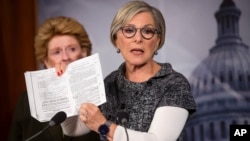 Senator Barbara Boxer (R) holds up a passage from the Affordable Care Act concerning health care benefits for women during a news conference on Capitol Hill in Washington, Sept. 30, 2013.