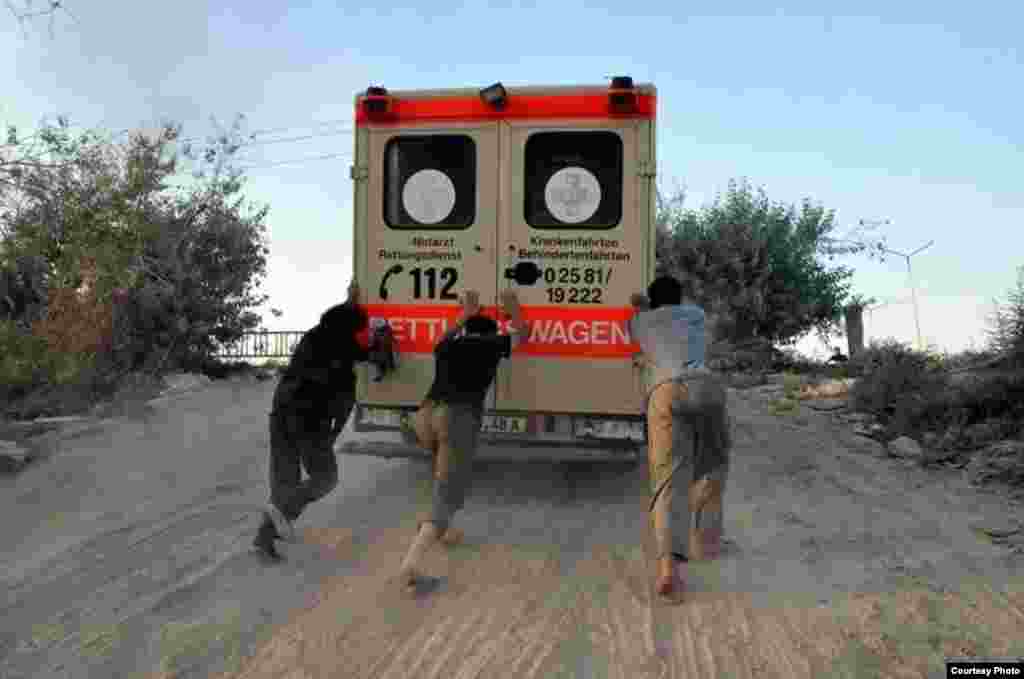 Abdul-Rahman (Peter) Kassig (center) helps push an ambulance up a hill during his time working with SERA. Photo taken near Deir Ezzor, August 2013. (Copyright, with permission to use from Kassig family)