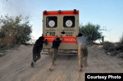 FILE - Abdul-Rahman (Peter) Kassig (center) helps push an ambulance up a hill during his time working with SERA. Photo taken near Deir Ezzor, August 2013. (Copyright, with permission to use from Kassig family)