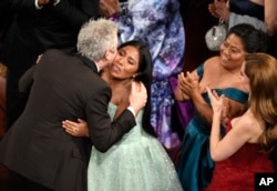 Yalitza Aparicio, right, congratulates Alfonso Cuaron in the audience as he is announced the winner of the award for best cinematography for "Roma" at the Oscars on Sunday, Feb. 24, 2019, at the Dolby Theatre in Los Angeles.