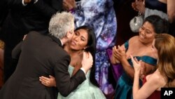 Yalitza Aparicio, right, congratulates Alfonso Cuaron in the audience as he is announced the winner of the award for best cinematography for "Roma" at the Oscars on Sunday, Feb. 24, 2019, at the Dolby Theatre in Los Angeles.