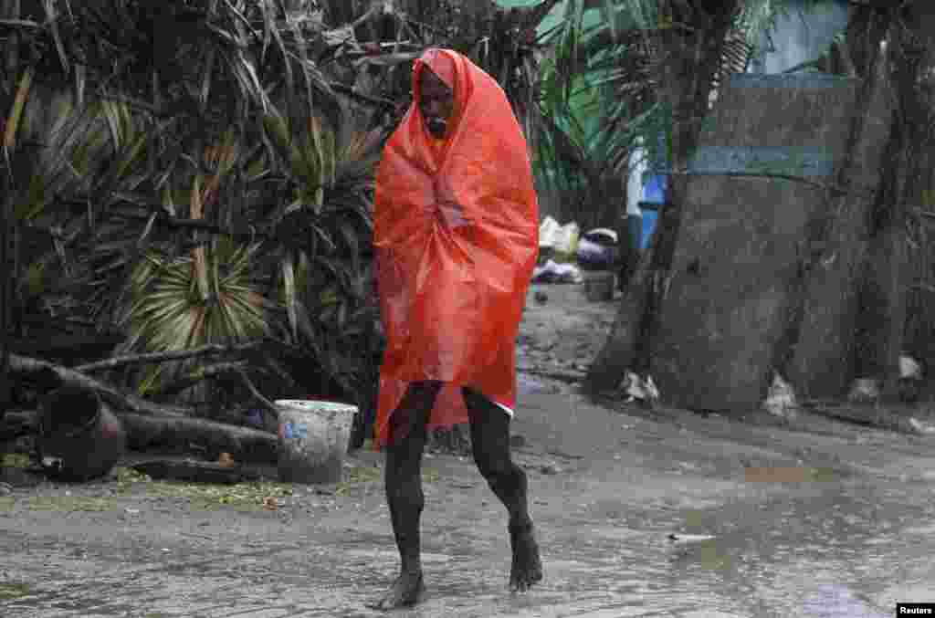 A man covers himself with a plastic sheet during heavy rain brought by Cyclone Phailin in the southern Indian state of Andhra Pradesh, Oct. 12, 2013.