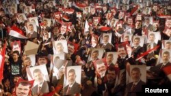 Para anggota Muslim Brotherhood dan pendukung presiden terguling Mohamed Morsi memegang posternya menyusul pernyataan kudeta dari militer (3/7). 