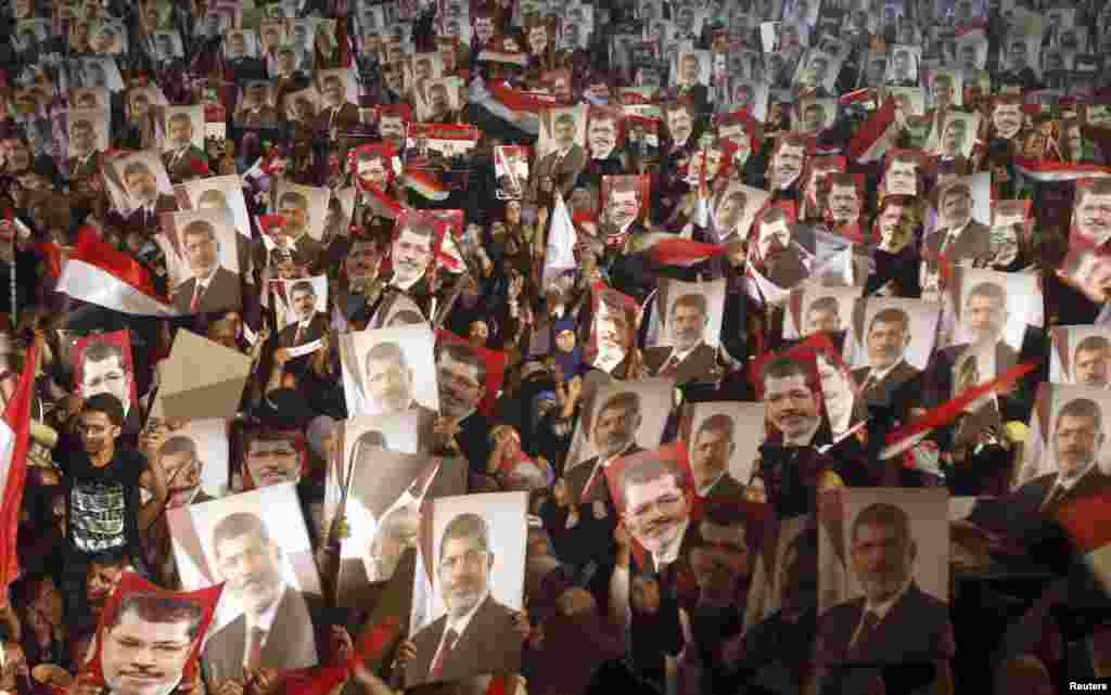 Members of the Muslim Brotherhood and supporters of Egypt's President Mohamed Morsi hold pictures of him as they react after the army's statement was read out on state TV, at the Raba El-Adwyia mosque square in Cairo, July 3, 2013. Egypt's armed forces overthrew elected Islamist President Morsi and announced a political transition with the support of a wide range of political, religious and youth leaders.
