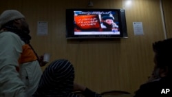 FILE - People watch a news report on TV about the leader of Pakistani Taliban leader Fazlullah Khurasani, at a coffee shop in Islamabad, Pakistan, Nov. 7, 2013.