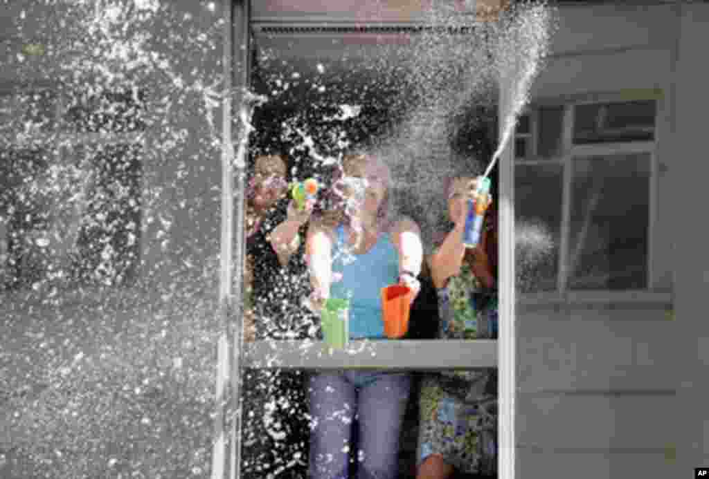 Women throw water and foam to pedestrians, from an office building in Montevideo's old district, Uruguay, 31 Dec 2010. (AFP Image)