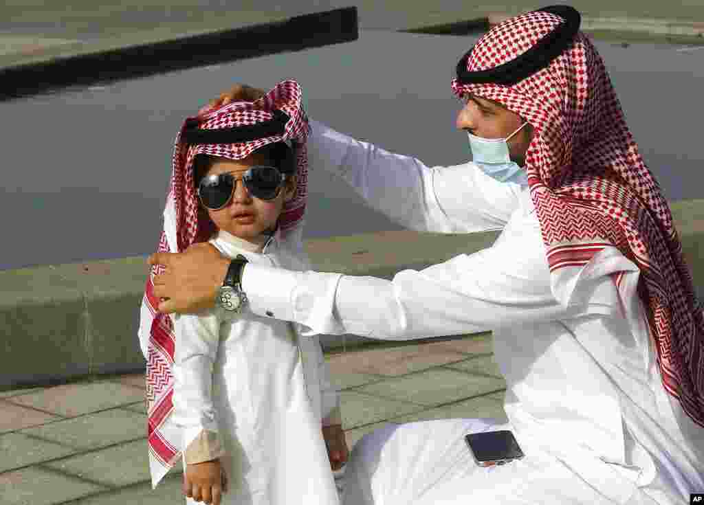 A Saudi man arranges his son&#39;s traditional &quot;Ghutra,&quot; or head cover, after performing Eid al-Fitr prayers marking the end of the holy fasting month of Ramadan in Jiddah, Saudi Arabia.