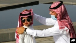 عید الفطر کے موقعے پر ایک سعودی شخص اپنے بچے کا روایتی سکارف درست کر رہا ہے۔ 13 مئی 2021 ۔ فوٹو اے پی 