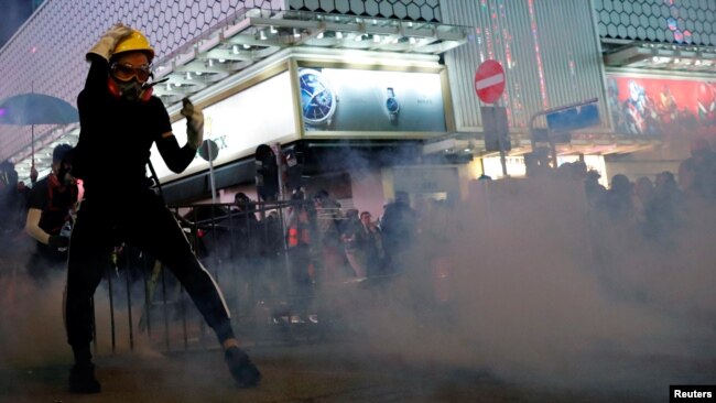 香港抗议者在警察施放的催泪弹烟雾中与港警对峙。（2019年10月20日）