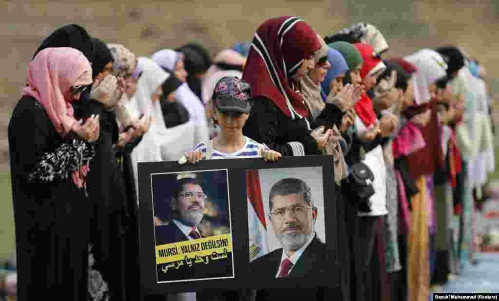 A supporter of Egypt's deposed Islamist President Mohamed Mursi and the Muslim Brotherhood displays a sign as others perform special prayers in downtown Kuala Lumpur August 17, 2013. Egypt's prime minister has proposed disbanding the Muslim Brotherhood of