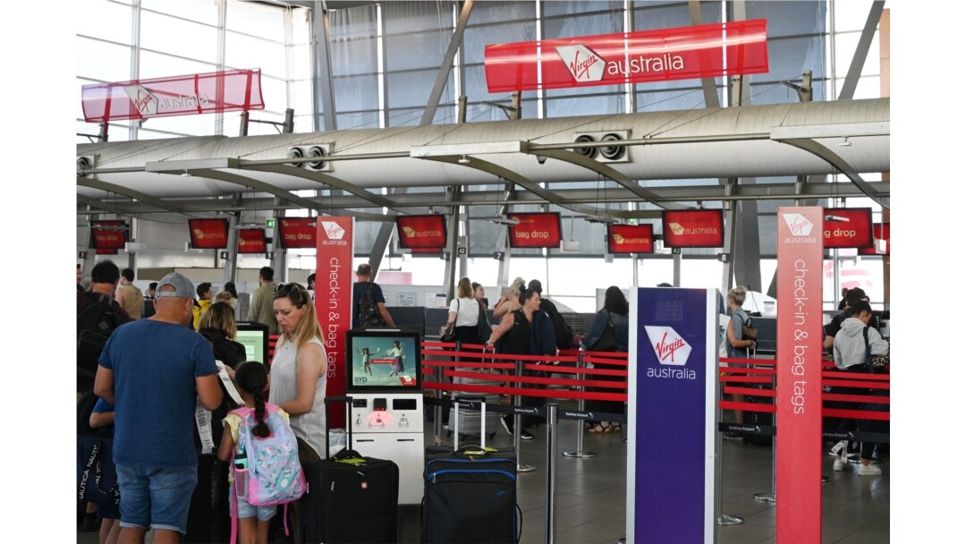 FILE - Travelers wait in line at a Virgin Australia Airlines counter at Kingsford Smith International Airport, amid the coronavirus outbreak, in Sydney, Australia, March 18, 2020.