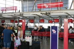 FILE - Travelers wait in line at a Virgin Australia Airlines counter at Kingsford Smith International Airport, amid the coronavirus outbreak, in Sydney, Australia, March 18, 2020.