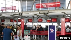 Travelers wait in line at a Virgin Australia Airlines counter at Kingsford Smith International Airport, amid the coronavirus outbreak, in Sydney, Australia, March 18, 2020.