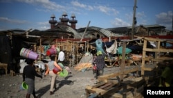 Machann kap pote machandiz pou yo al vann toupre kote mache a te boule nan sant vil Pòtoprens. (Foto REUTERS/Andres Martinez Casares) 21 fevriye 2018. 