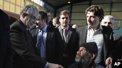 Greece's Prime Minister Lucas Papademos, left, greets a homeless man during a New Year's meal for the homeless people distributed by the municipality of Athens, January 1, 2012.