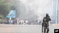 Malijski vojnik kraj zapaljene barikade ispred logora pobunjene padobranske jedinice u Bamaku