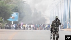 A soldier patrols near a burning road block outside the paratrooper camp, home of the former president's Red Beret presidential guard, in Bamako, February 8, 2013.