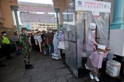 Umat Muslim berjalan melalui ruang desinfeksi yang dipasang untuk mengekang penyebaran wabah virus corona saat mereka memasuki kompleks Masjid Agung Al Mashun untuk menghadiri salat Idulfitri di Medan, Sumatera Utara, Kamis, 13 Mei 2021.