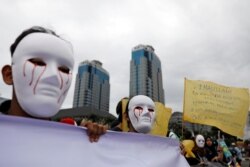 Para wartawan Indonesia mengenakan topeng saat mengikut pawai Hari Buruh di Museum Nasional (Monas), Jakarta, 1 Mei 2019. (Foto: Reuters)