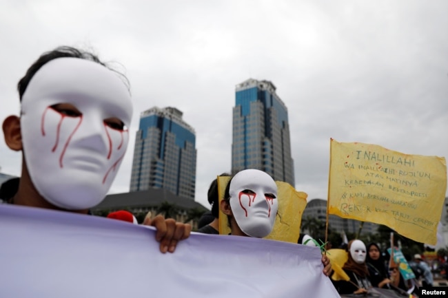 Para wartawan mengenakan topeng saat mengikut pawai Hari Buruh di Museum Nasional (Monas), Jakarta, 1 Mei 2019. (Foto: Reuters)