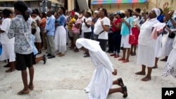 A Catholic nun kneels in prayer during a pause in a procession marking the feast of Corpus Christi in Port-au-Prince, Haiti, May 26, 2016. A review of last year's contested presidential and legislative elections is to be released Sunday.