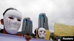 Para wartawan Indonesia mengenakan topeng saat mengikut pawai Hari Buruh di Museum Nasional (Monas), Jakarta, 1 Mei 2019. (Foto: Reuters)