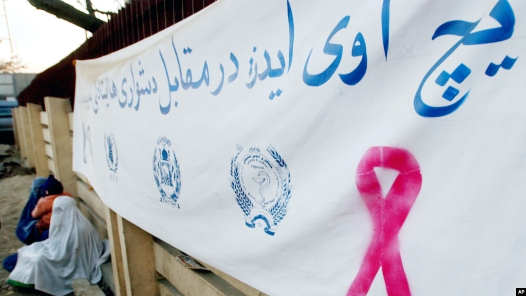 Para perempuan di Afghanistan duduk di bawah spanduk bertuliskan "HIV/AIDS, Lawan Kesulitan, Ini Tanggung Jawab Semua Orang.". (Foto: Dok)