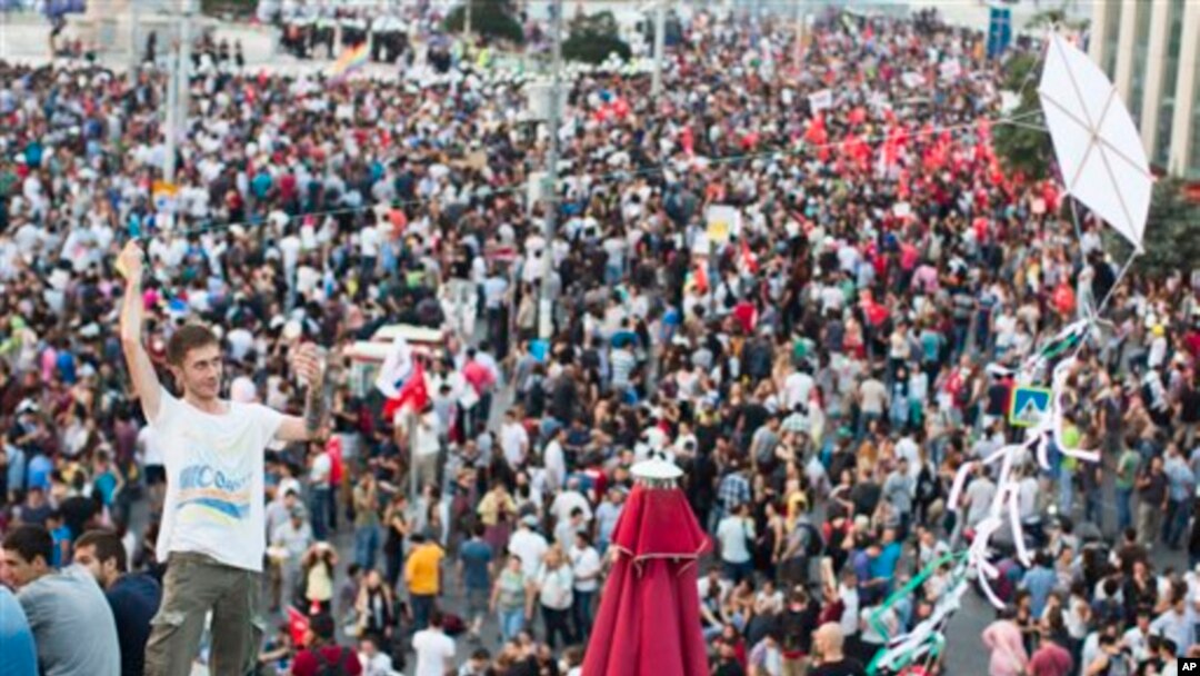 Seorang pria menerbangkan layang-layang di atas atap di lapangan Taksim, Istanbul, Turki, saat berlangsungnya aksi protes menuntut keadilan bagi seorang demonstran yang tewas akibat tembakan polisi bulan ini (29/6).