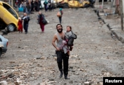 FILE - A man cries as he carries his daughter while walking from an Islamic State-controlled part of Mosul toward Iraqi special forces soldiers during a battle in Mosul, Iraq, March 4, 2017.