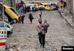 FILE - A man cries as he carries his daughter while walking from an Islamic State-controlled part of Mosul towards Iraqi special forces soldiers during a battle in Mosul, Iraq, March 4, 2017.