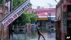 A man wades through water after heavy rains flooded the premises of a COVID-19 hospital being set up at Ghaziabad, on the outskirts of New Delhi, India, May 23, 2021.