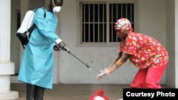 Un employé de la Croix-Rouge libérienne désinfecte les mains d'une personne suspectée d'avoir touché un malade d'Ebola, Monrovia, septembre 2014. (Crédit: alerte internationale)