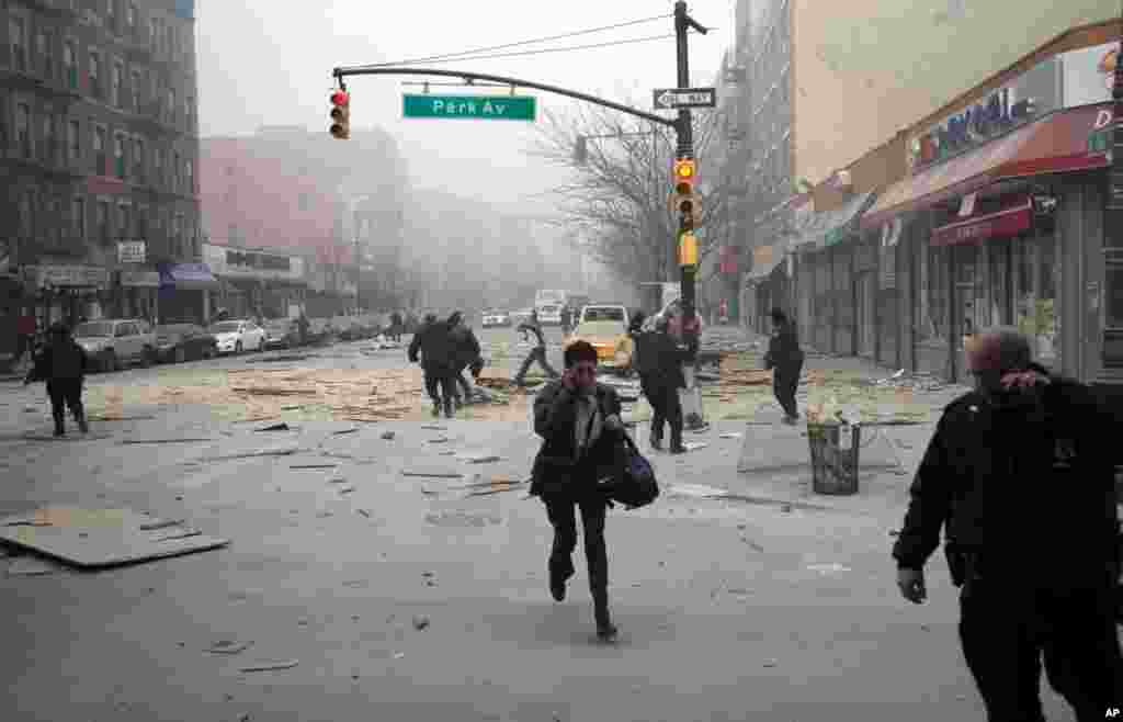 People run after an explosion and building collapse in Harlem, New York, March 12, 2014.