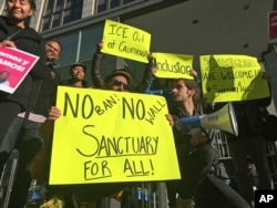 FILE - Protesters hold up signs outside a courthouse where a federal judge will hear arguments in the first lawsuit challenging President Donald Trump's executive order to withhold funding from communities that limit cooperation with immigration authorities in San Francisco, April 14, 2017.
